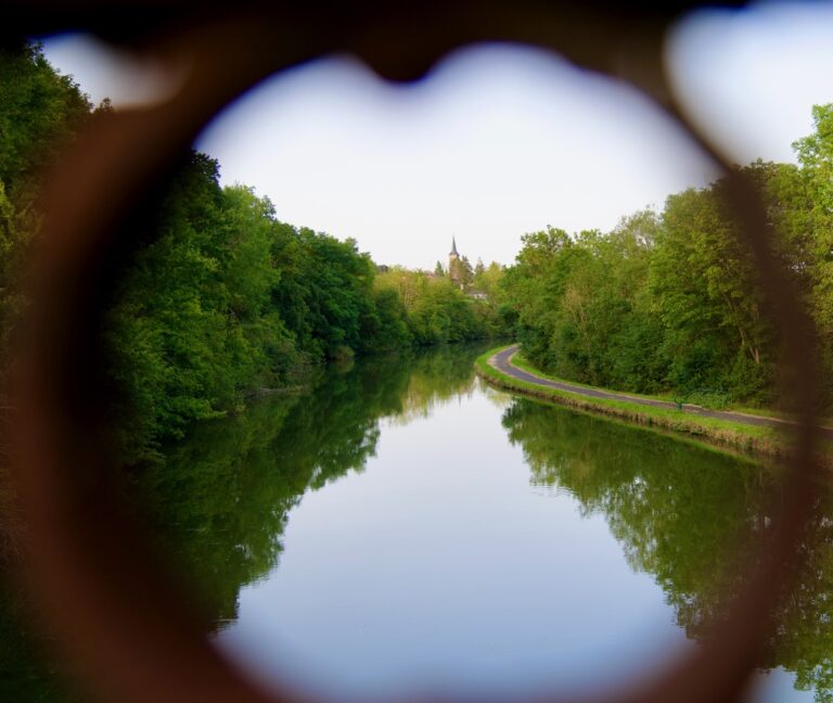 Urlaub mit Fibromyalgie: Blick durch Herz auf Fluss mit Kirche in Frankreich – Fotografie als Ausgleich
