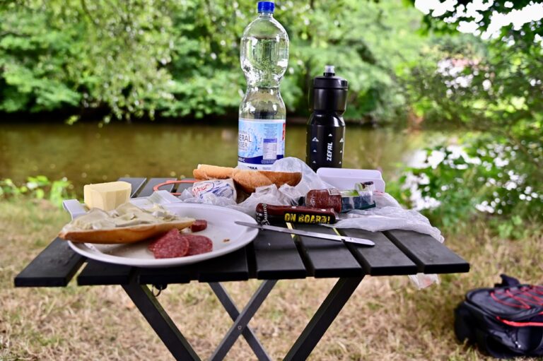 Urlaub mit Fibromyalgie: Picknick mit Käse und Wein am Flussufer in Frankreich